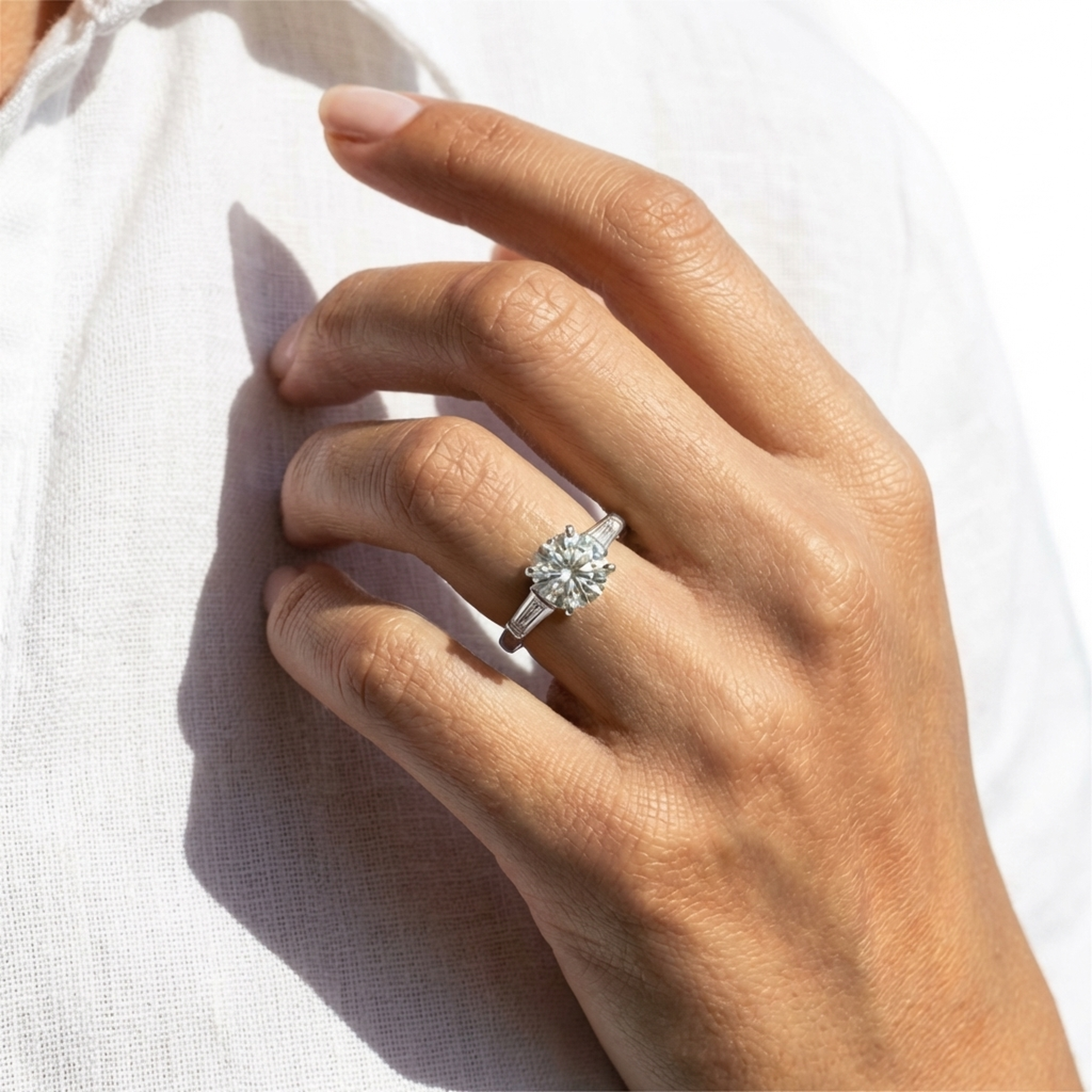 ARIAH BELVI round diamond trilogy engagement ring in platinum on hand with natural sunlight