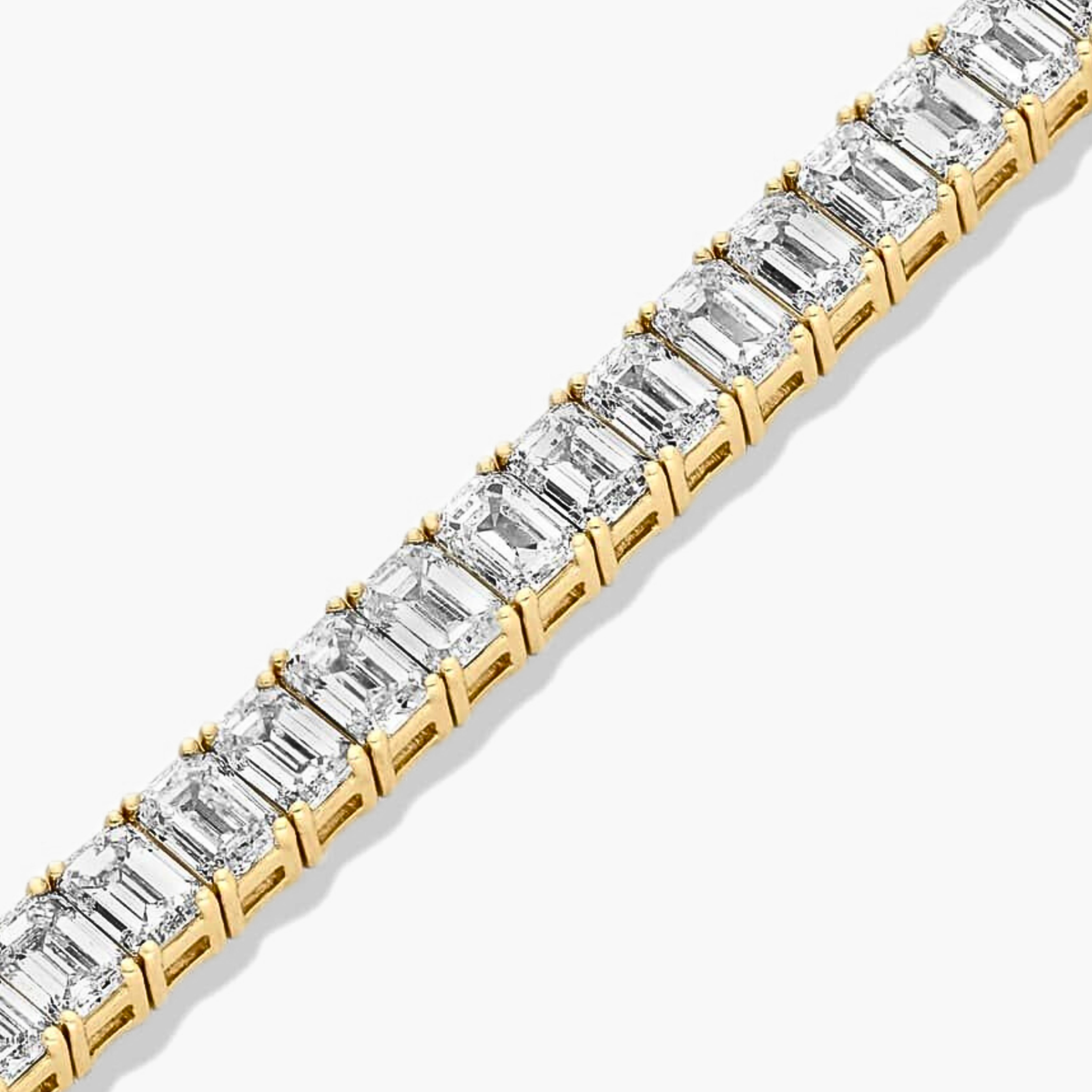 Close-up view of emerald cut diamond tennis bracelet in yellow gold